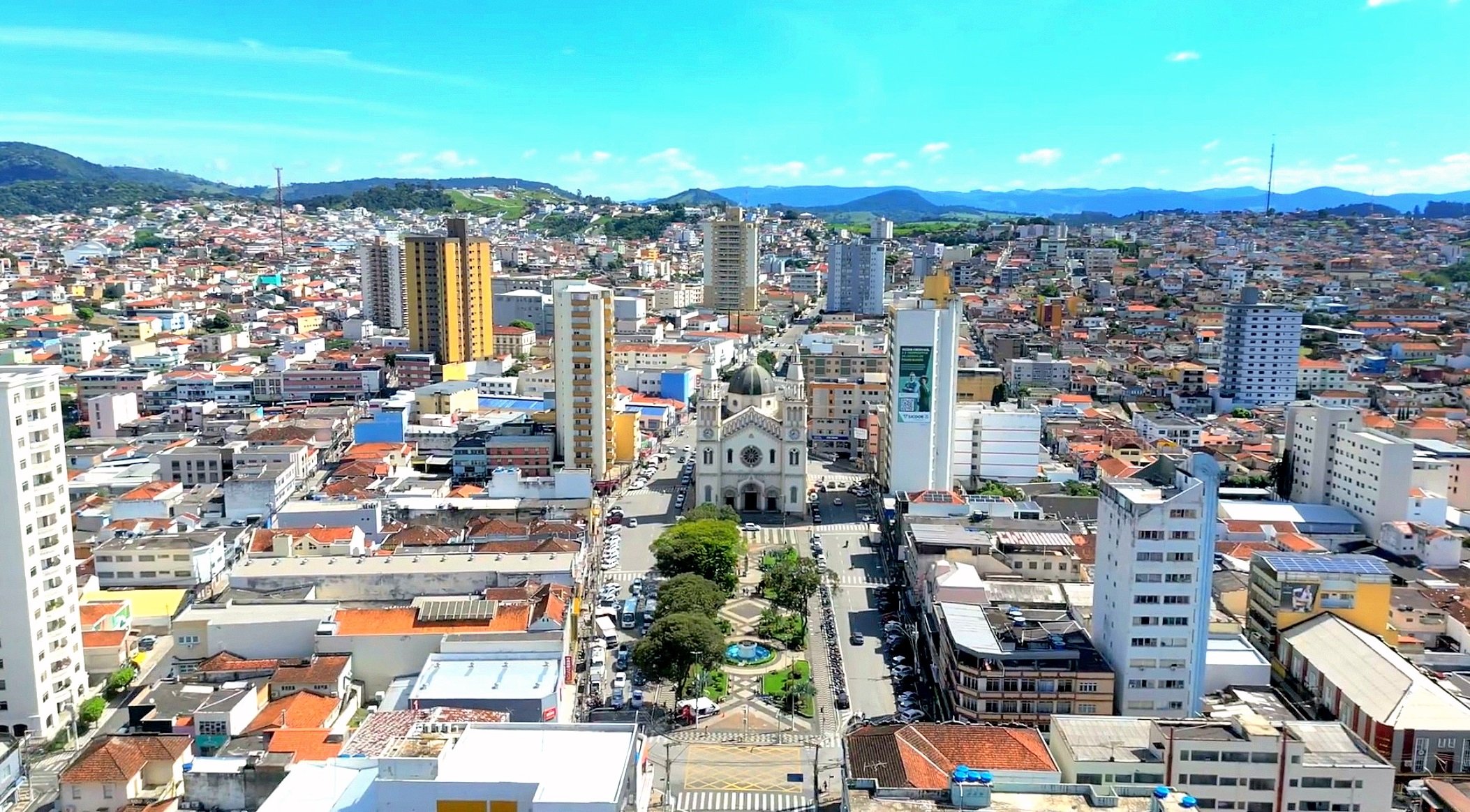 Vista aérea do centro de Pouso Alegre MG, com a igreja matriz e serras ao fundo, no entardecer