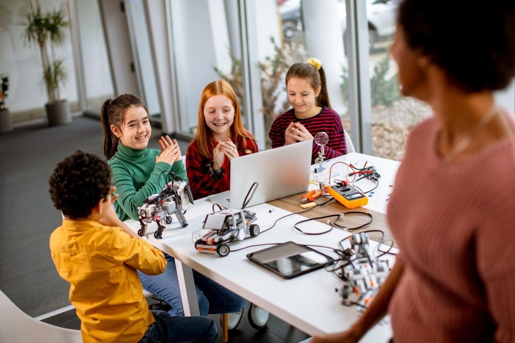 Sala de aula com educador em atividade, projetor e estudantes