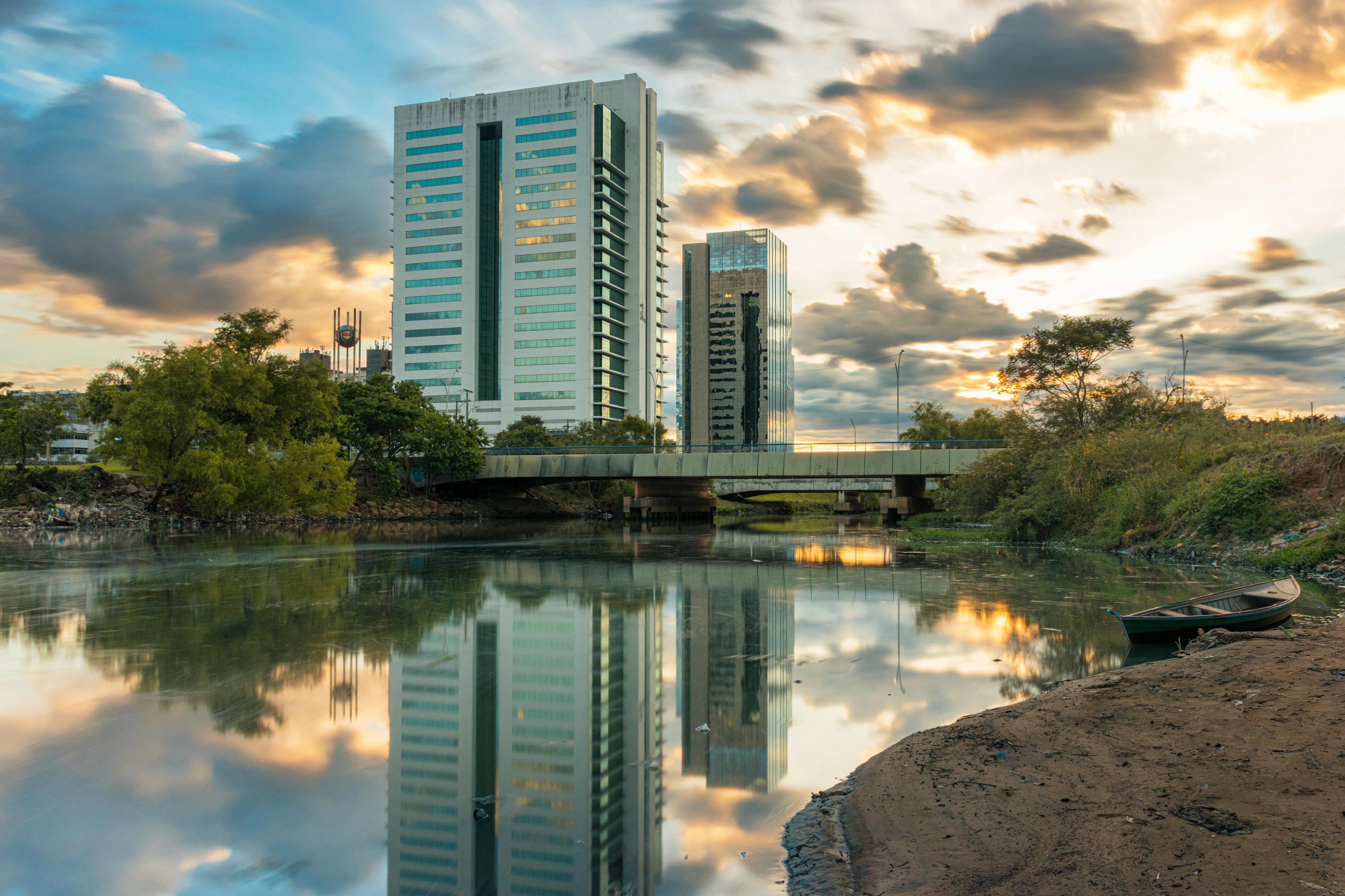 Porto Alegre ao entardecer, com o Guaíba em primeiro plano e prédios refletidos na água