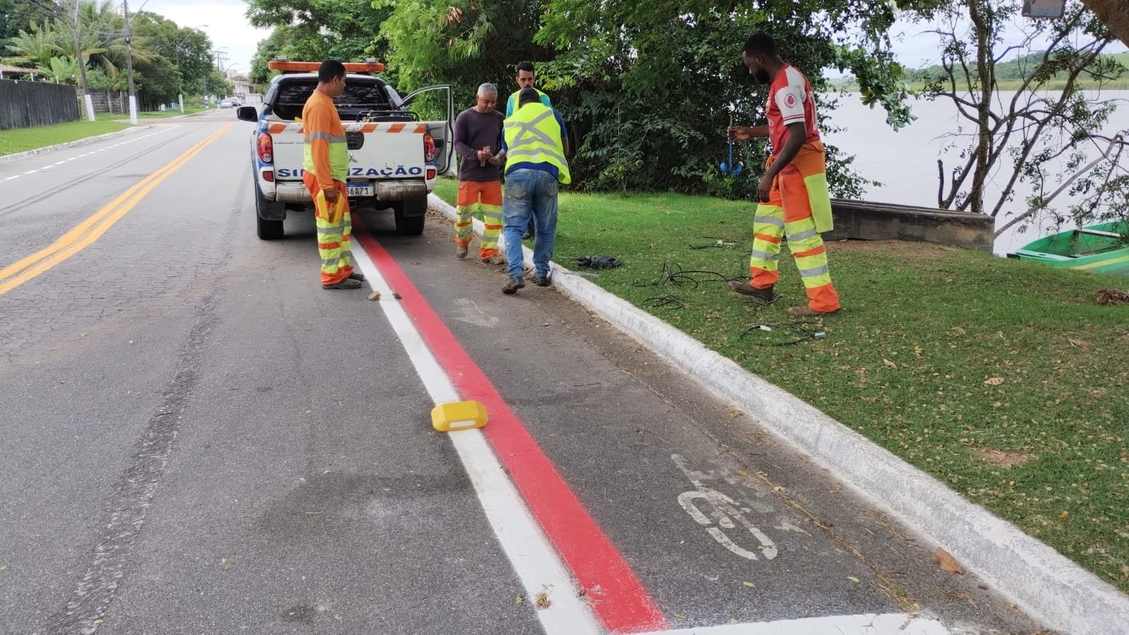 Trabalho de manutenção urbana em via pública, com equipe realizando serviços de sinalização e reparo leve