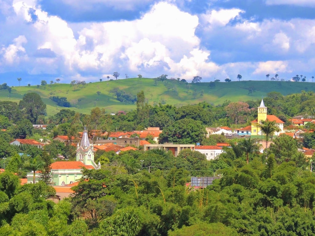 Paisagem urbana de interior com morros verdes ao fundo, remetendo a cidades da região serrana capixaba