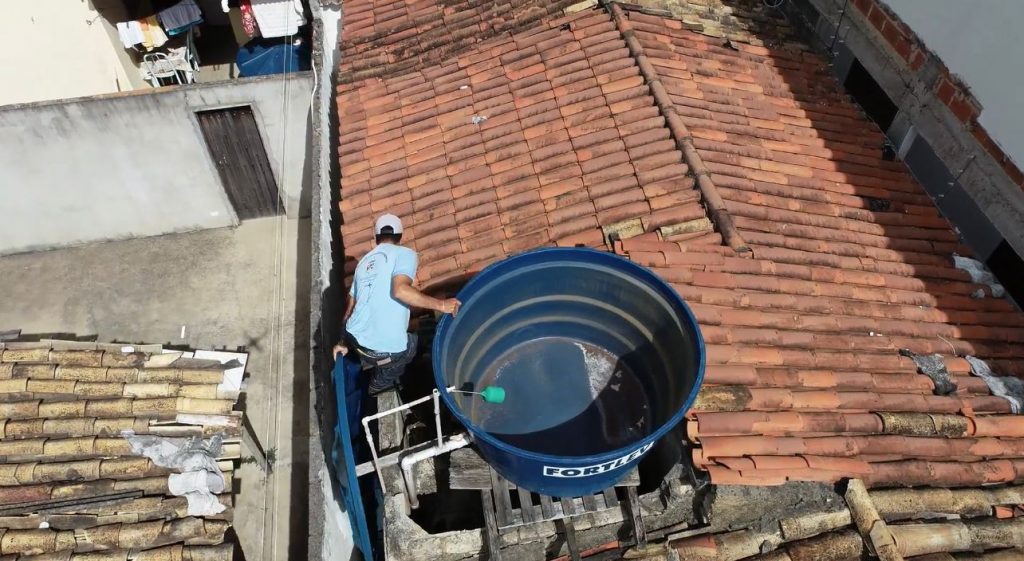 Agente de combate às endemias em atividade de campo, vistoriando e aplicando larvicida