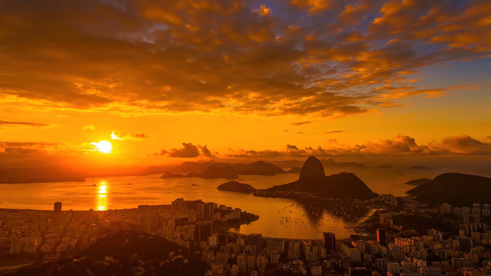 Vista aérea de Volta Redonda RJ ao pôr do sol, com o rio Paraíba do Sul e a malha urbana ao fundo