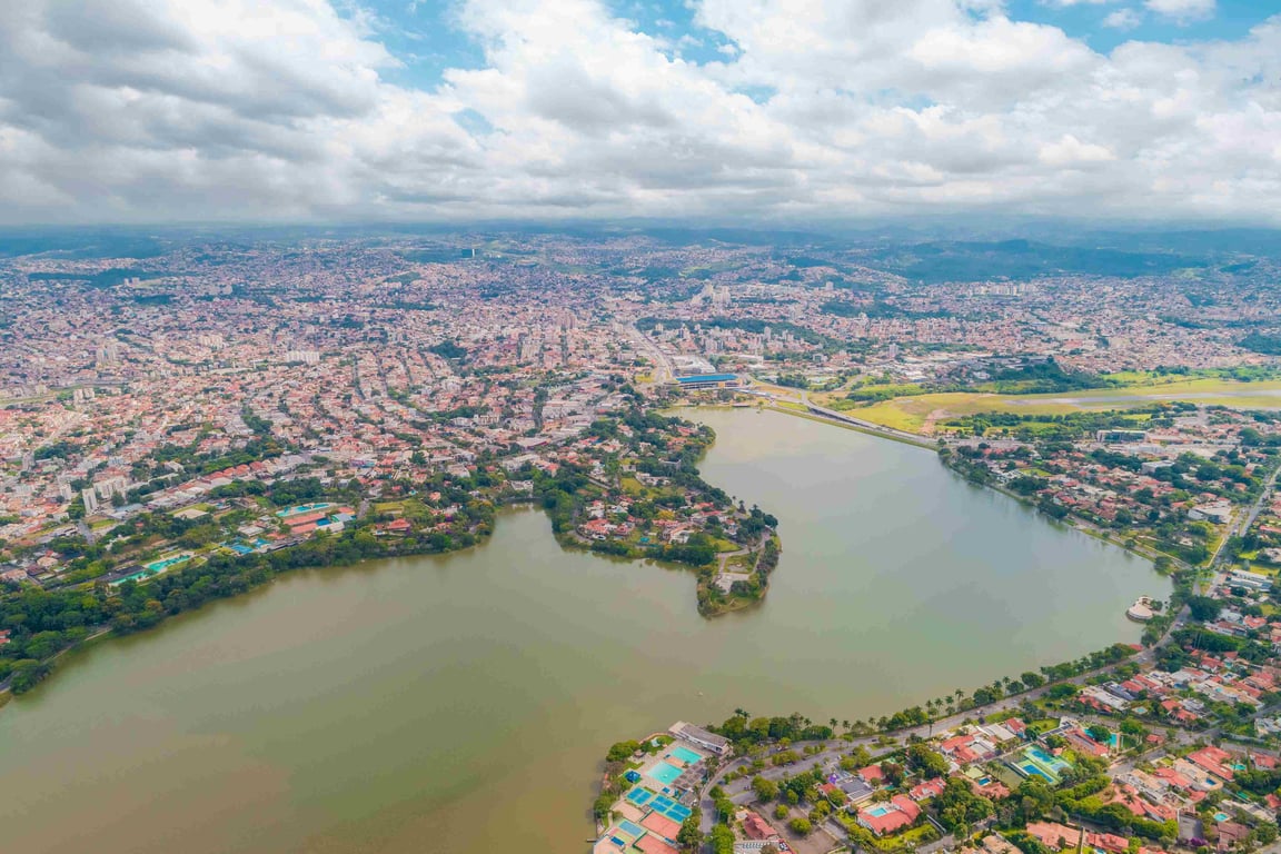 Vista panorâmica da Lagoa da Pampulha com prédios de Belo Horizonte ao fundo, ao entardecer