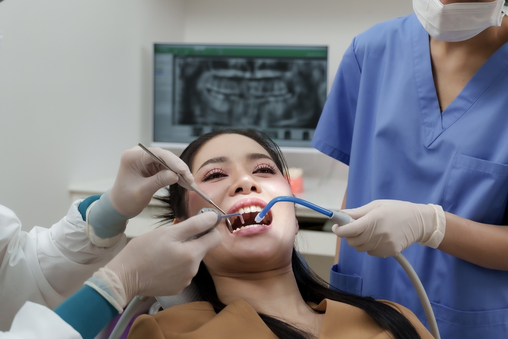 Dentista em atendimento em consultório público, equipe utilizando EPI