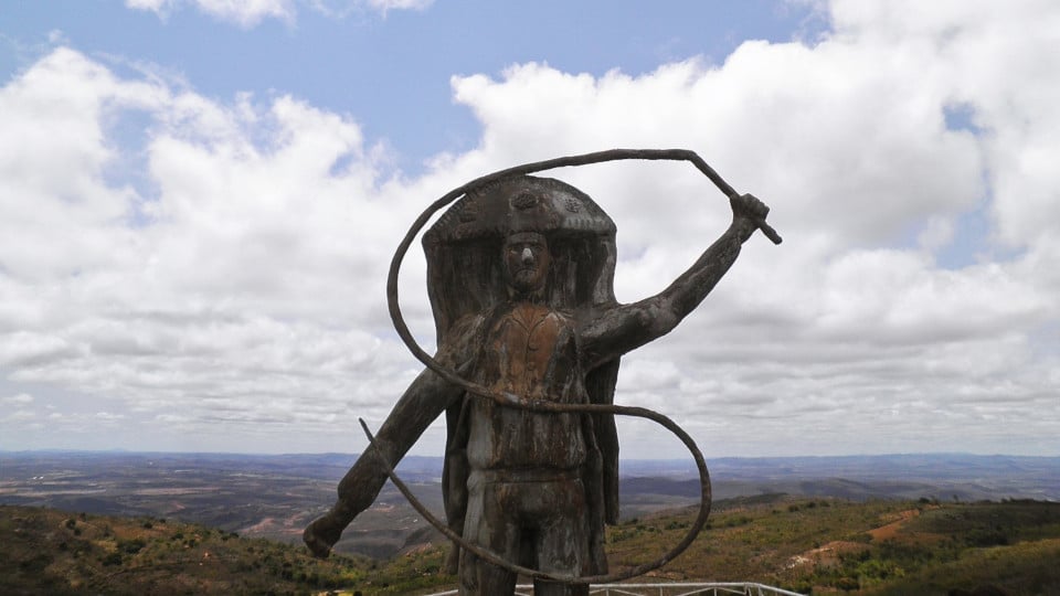 Vista do sertão paraibano em paisagem ampla, com escultura em mirante e horizonte ao fundo