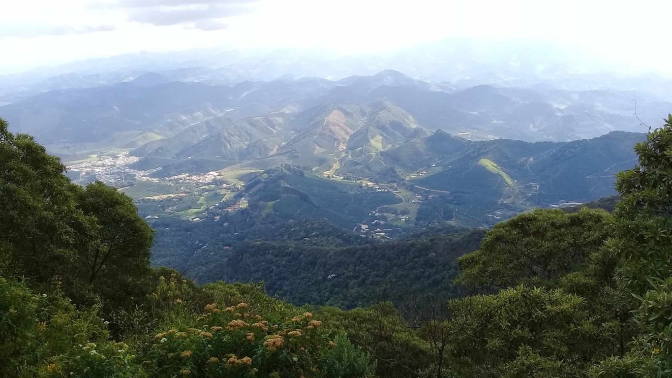Montanhas do Parque Nacional do Caparaó ao amanhecer, com vegetação densa no primeiro plano e vales ao fundo