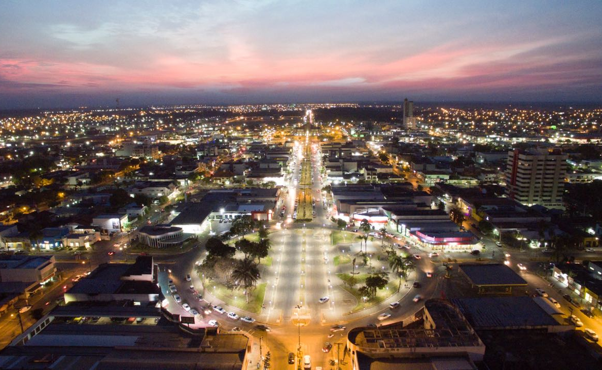 Vista aérea de Sinop, Mato Grosso, com avenidas e áreas urbanas iluminadas ao entardecer