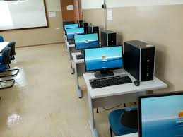 Sala de aula com computadores dispostos em mesas, quadro branco ao fundo, ambiente educacional em instituição federal