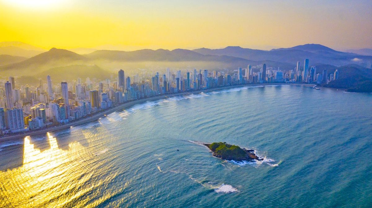 Vista panorâmica da orla de Balneário Camboriú ao entardecer, com arranha-céus ao fundo