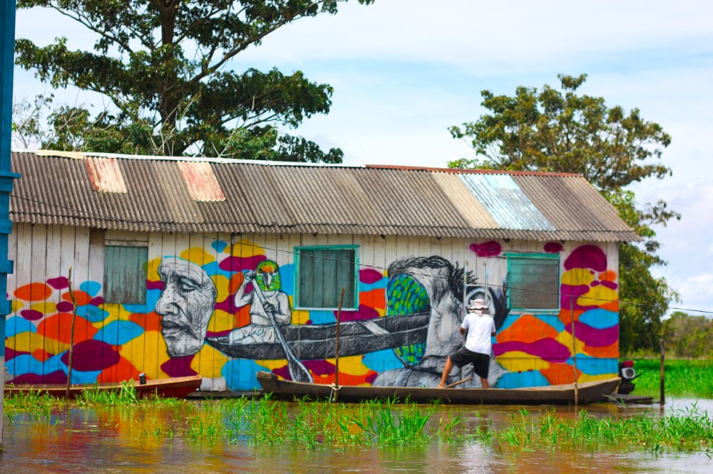 Casa de palafita e canoa em comunidade ribeirinha amazônica ao entardecer