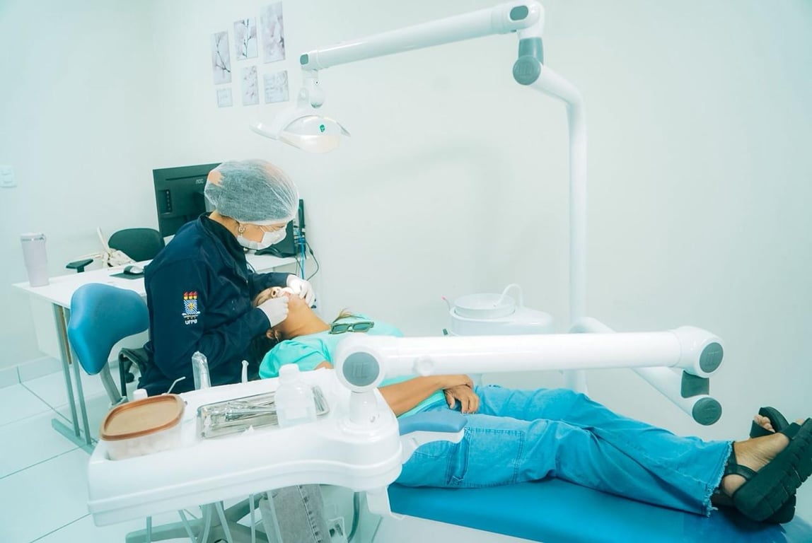 Profissional de saúde bucal atendendo paciente em consultório odontológico