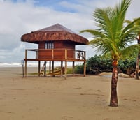 Orla de praia em Bertioga, com posto de observação de guarda-vidas e o mar ao fundo.