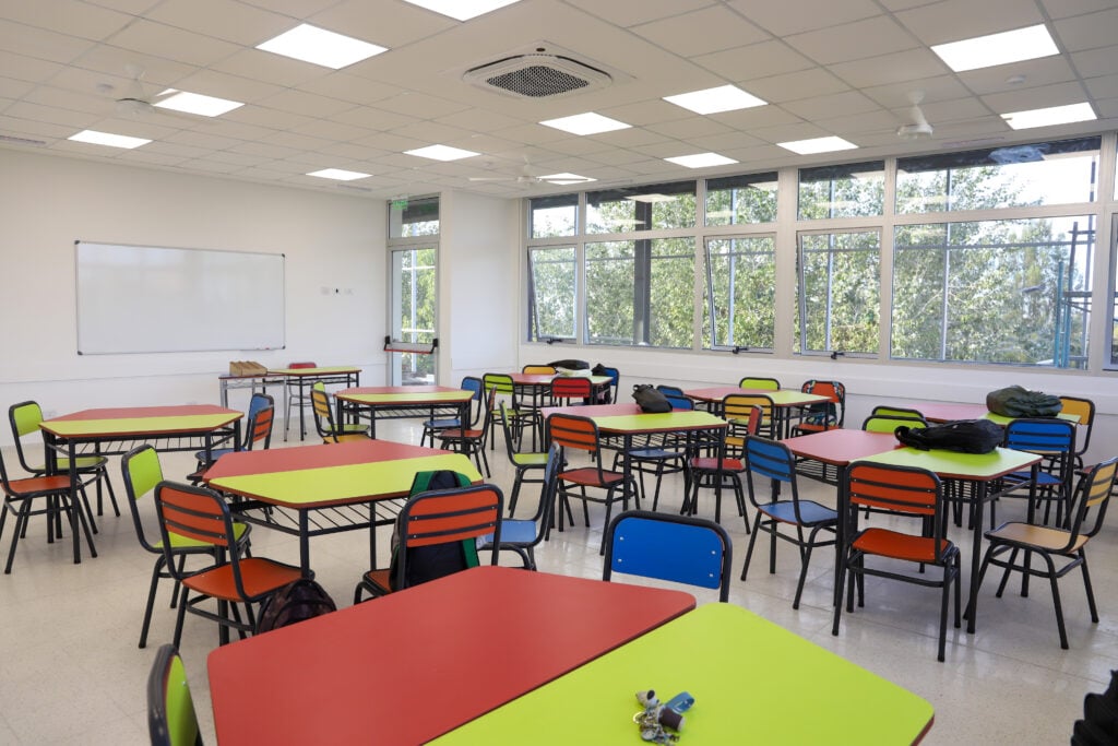 Sala de aula universitária moderna, com mesas e cadeiras coloridas, ambiente iluminado e preparado para atividades acadêmicas