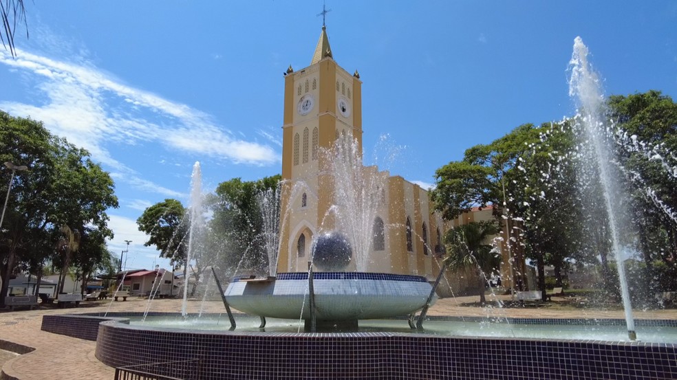 Centro de Parapuã, SP, com igreja e fonte na praça central em dia ensolarado