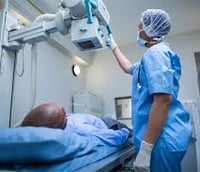 Técnico em radiologia operando equipamento de raio-X em ambiente hospitalar.