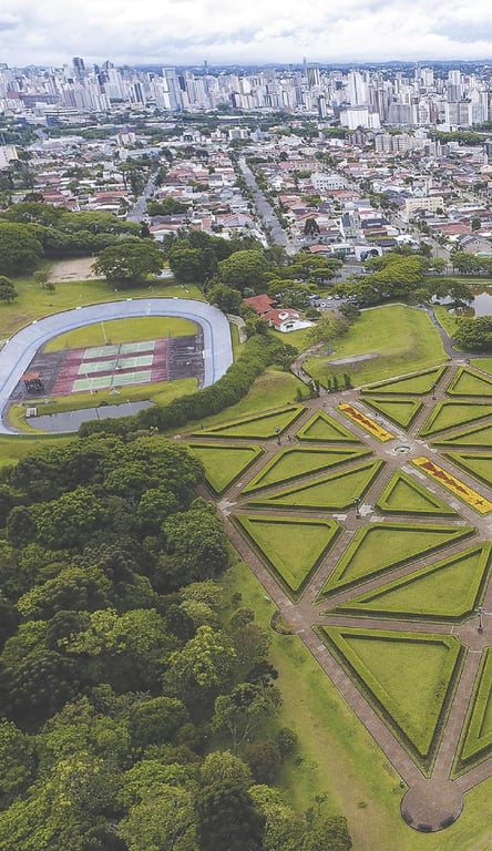 Vista aérea urbana com áreas verdes e edificações ao fundo, representando uma cidade do interior paulista