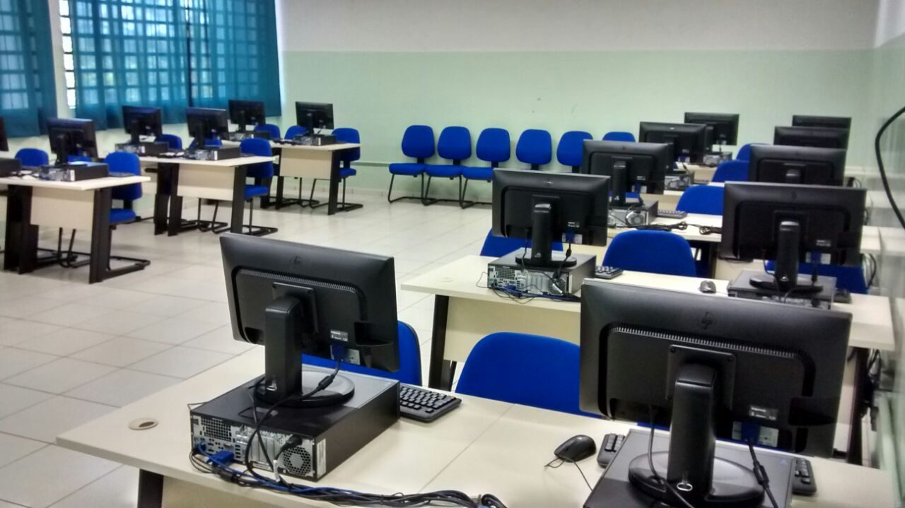 Laboratório educacional com computadores dispostos em mesas, ambiente técnico