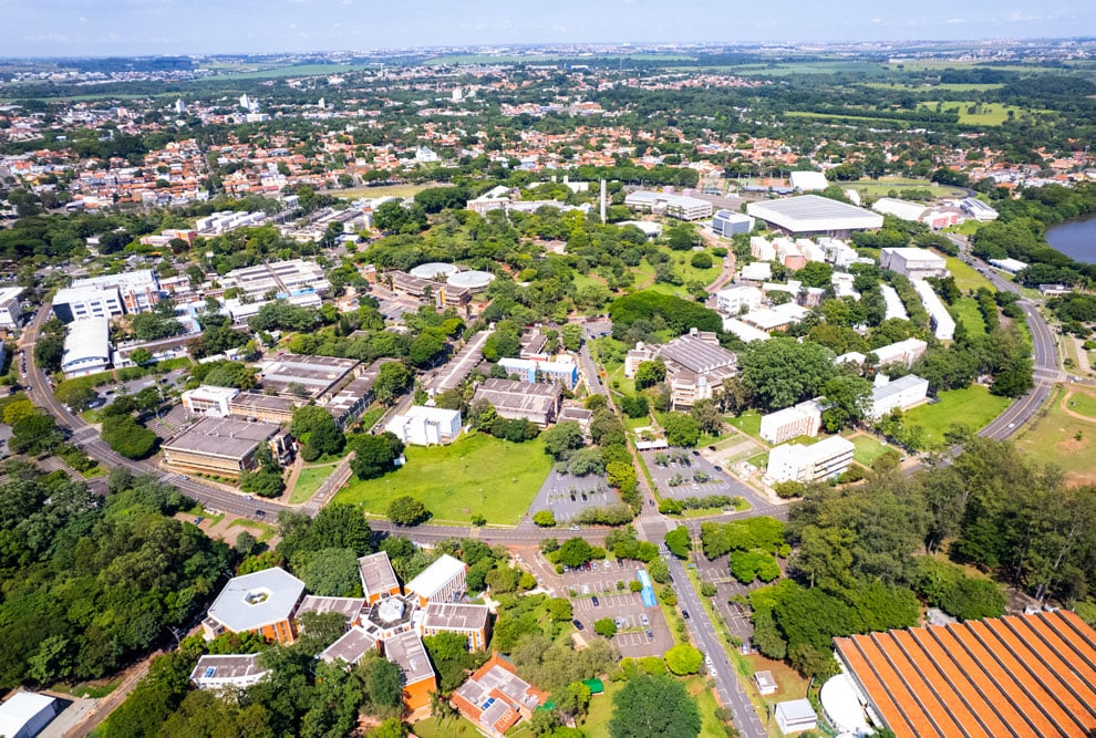 Vista aérea do campus da Unicamp em Campinas SP, com edifícios e áreas verdes.