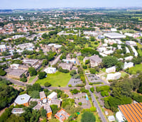 Vista aérea do campus da Unicamp em Campinas SP, com edifícios e áreas verdes.
