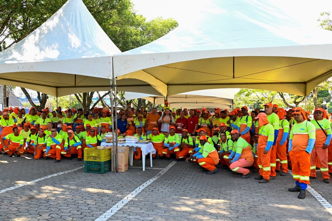 Equipe de limpeza urbana trabalhando em via pública, com uniformes laranja
