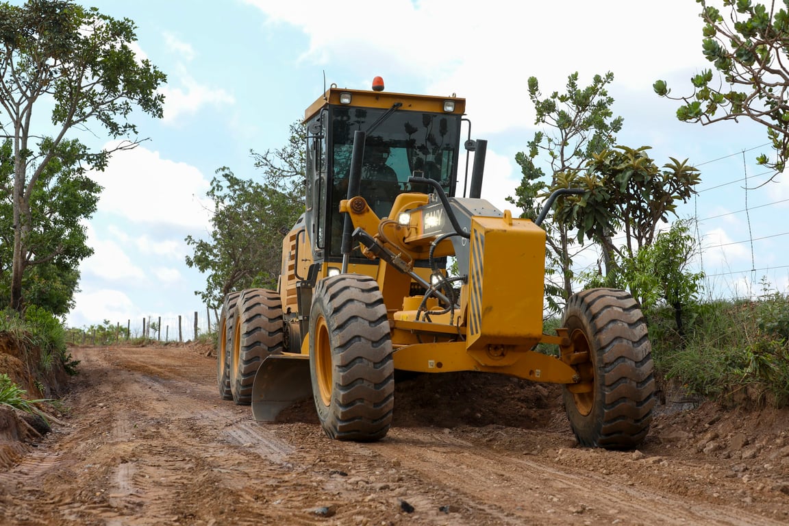 Motoniveladora operando em estrada de terra na zona rural