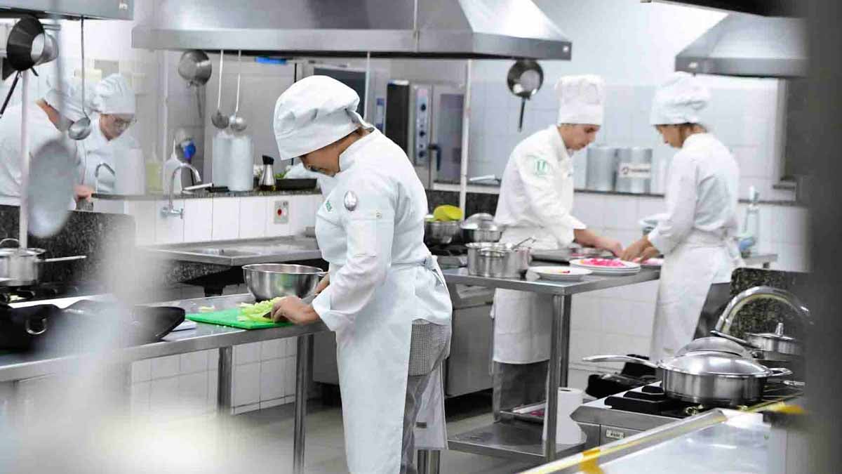 Ambiente de ensino culinário com cozinha profissional e alunos uniformizados