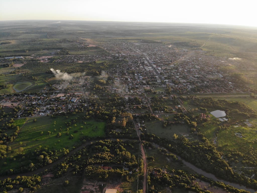 Vista aérea de uma pequena cidade em Mato Grosso, com telhados vermelhos, vegetação e vias de terra ao fundo