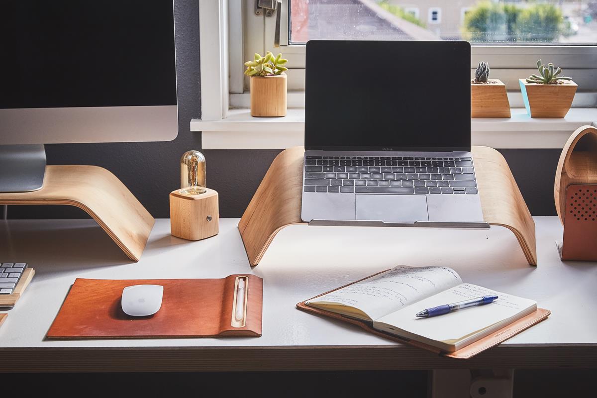 Mesa de trabalho administrativa com notebook, caderno e caneta em ambiente moderno e organizado