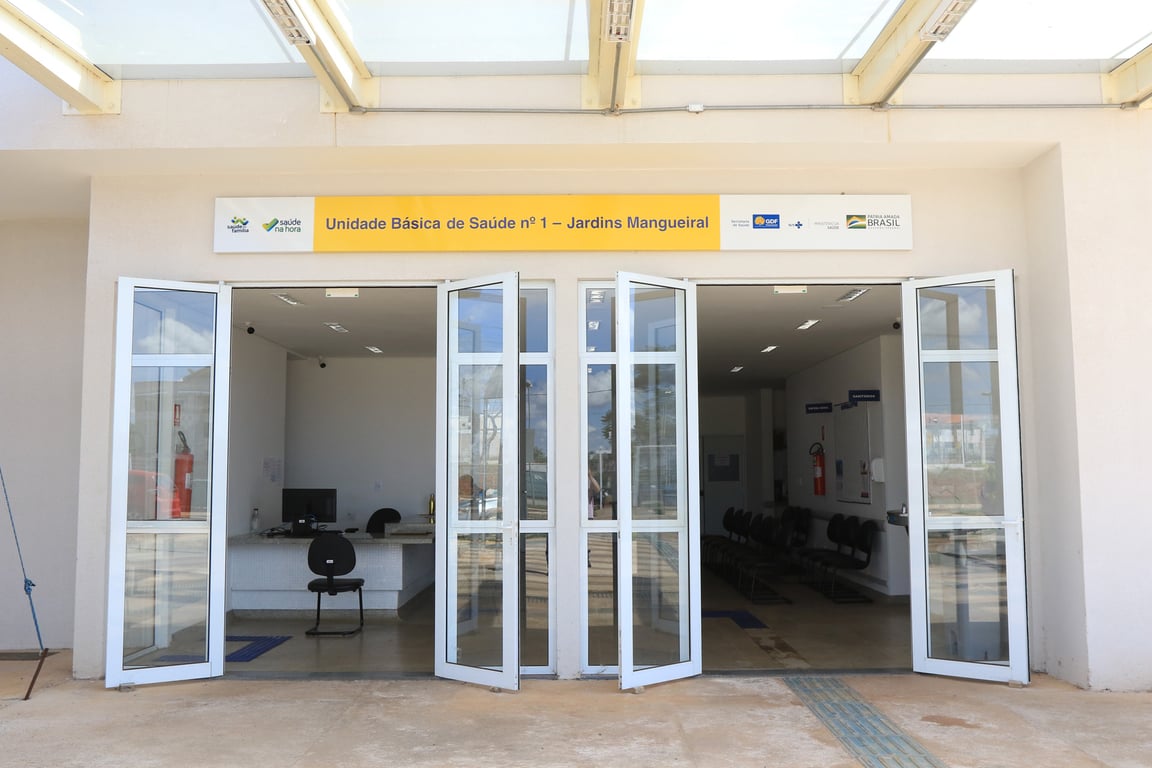Fachada de uma unidade básica de saúde no Brasil, com portas abertas e recepção visível.