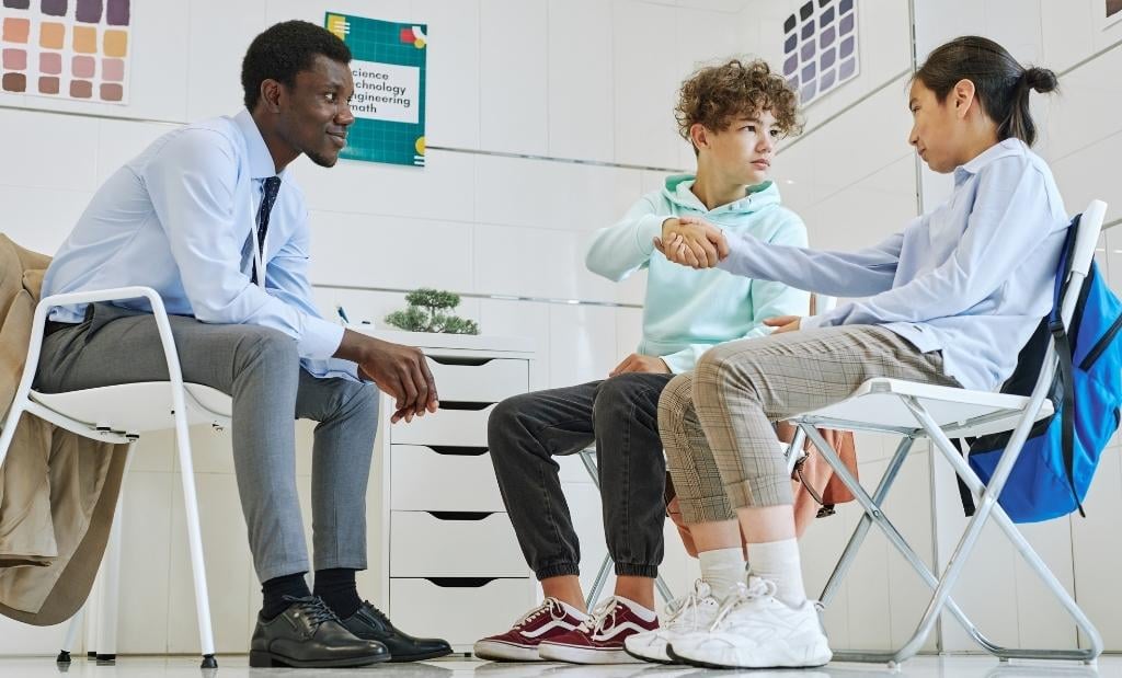 Docentes e gestor escolar dialogando sobre convivência e mediação de conflitos, em ambiente escolar.