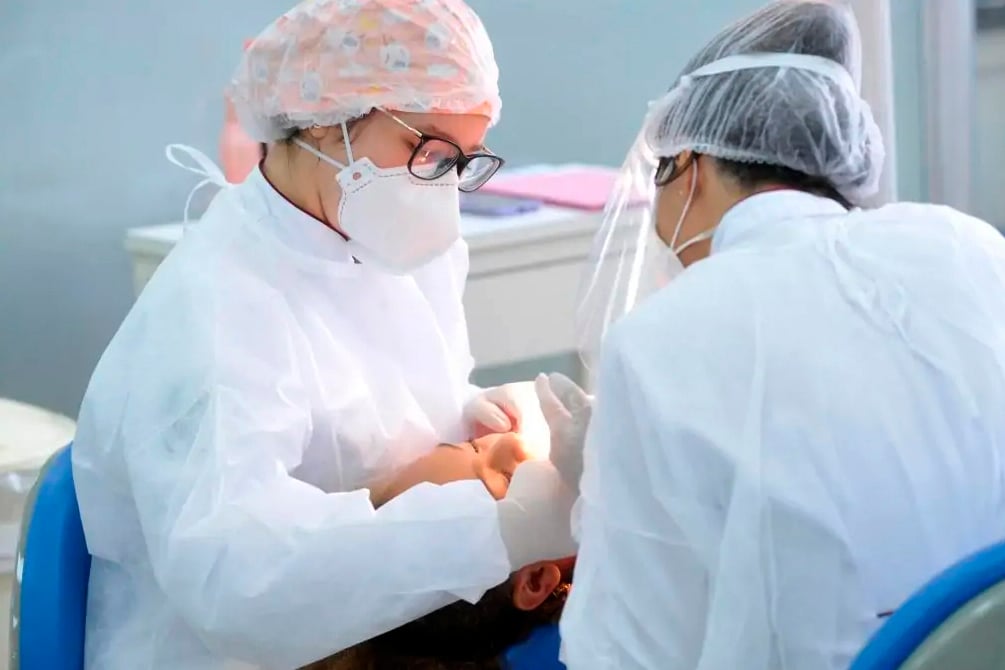 Atendimento odontológico em clínica pública no Brasil, com profissional usando EPI