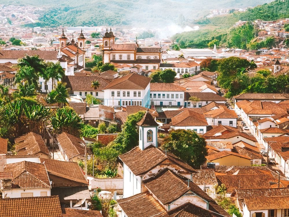 Vista panorâmica do centro histórico de Ouro Preto, com casario colonial e igrejas barrocas ao entardecer.