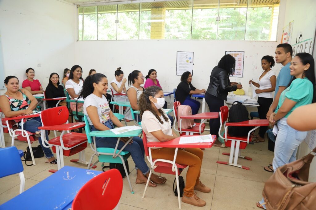 Sala ampla com candidatos durante aplicação de prova, em ambiente de concurso público