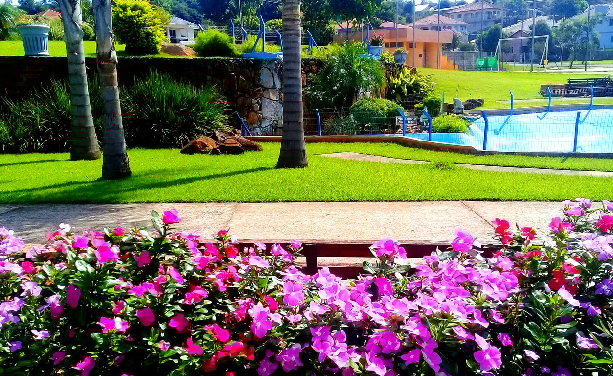 Praça e área central de um pequeno município no Noroeste do RS, com jardins floridos e igreja ao fundo