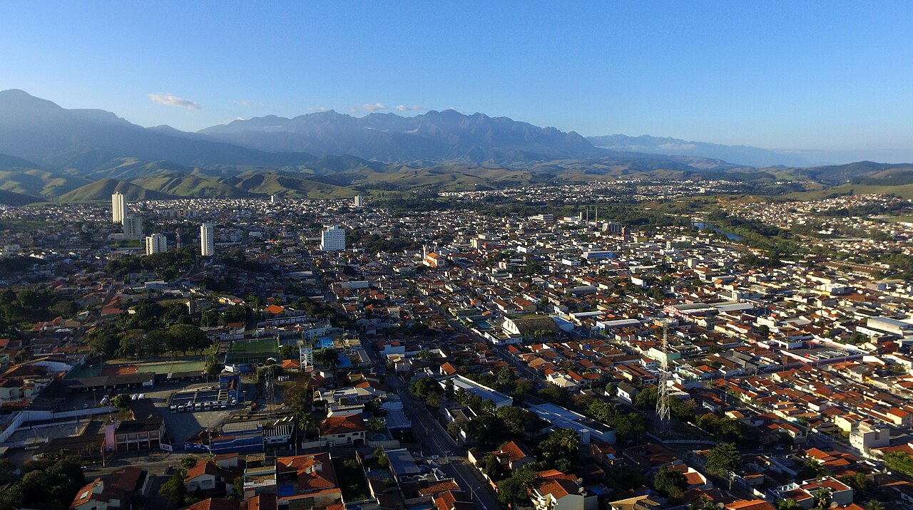 Vista aérea de cidade do interior paulista, com avenida arborizada e prédios baixos ao fundo de céu azul