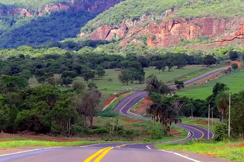 Estrada rural no Cerrado goiano ao pôr do sol, com lavouras ao fundo