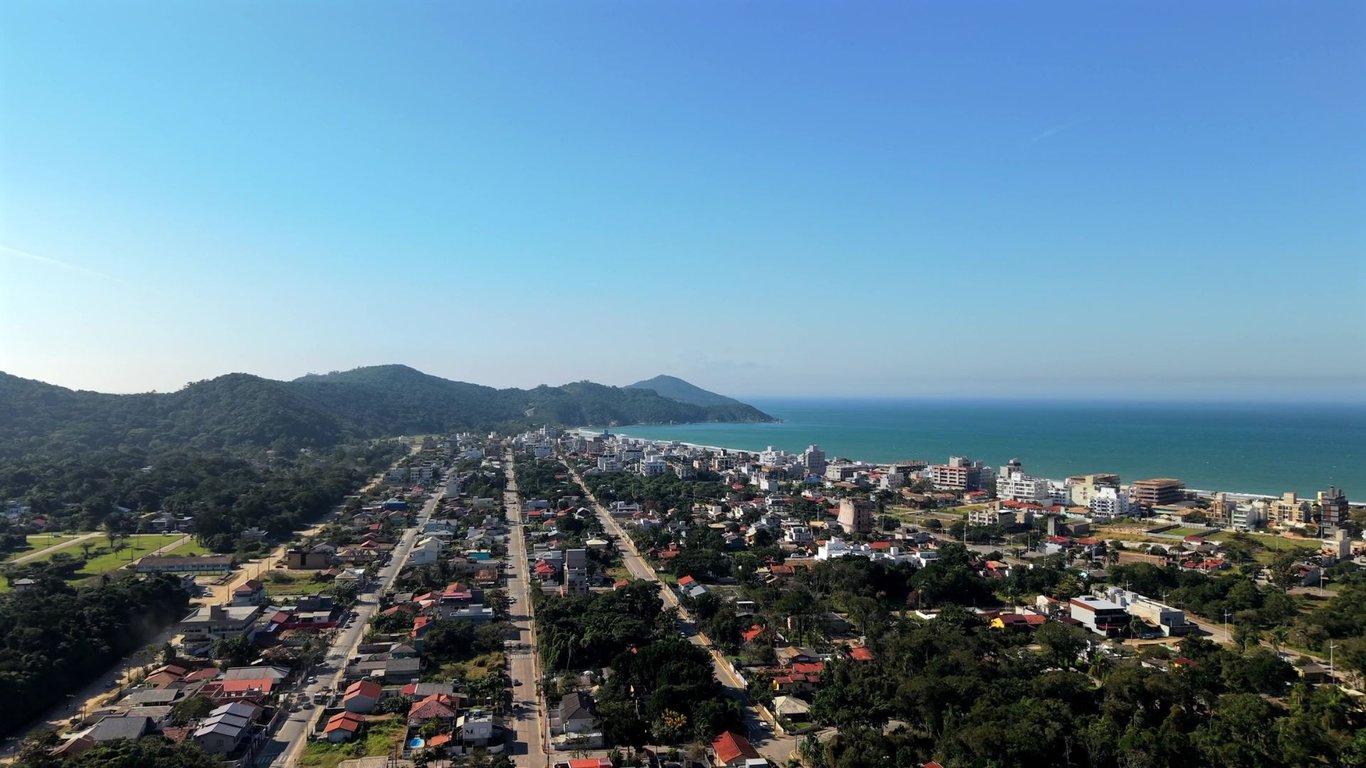Vista aérea da Praia de Bombinhas SC, com mar azul e céu aberto.