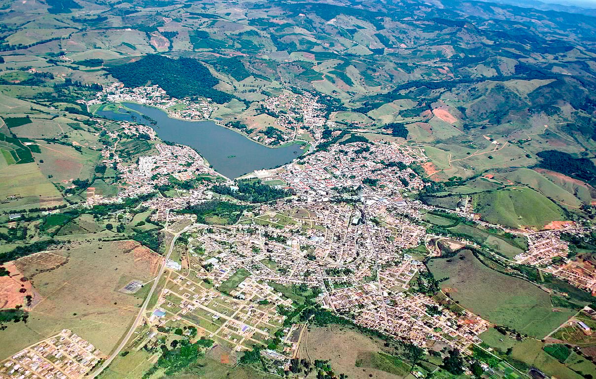 Cenário urbano típico de pequenas cidades brasileiras, com áreas verdes e construções baixas, em composição horizontal