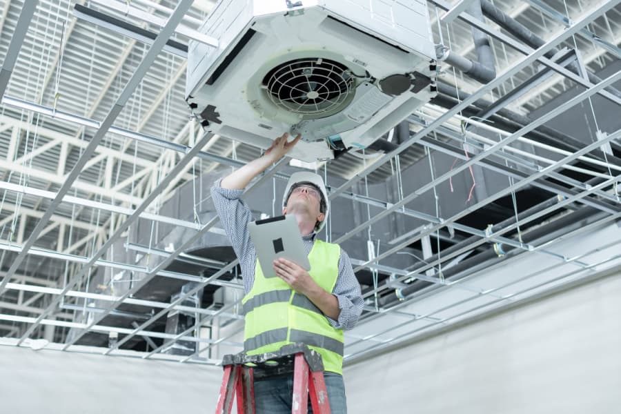 Profissional de manutenção em corredor hospitalar ajustando equipamento de ar-condicionado