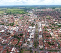 Vista panorâmica da Estância Turística de Olímpia, com área urbana e campos verdes ao fundo.