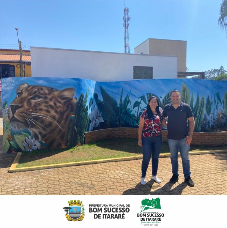 Mural artístico com onça em área urbana de Bom Sucesso de Itararé; duas pessoas posam à frente