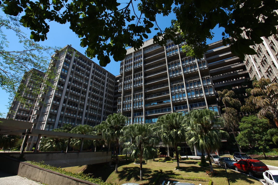 Fachada do campus Maracanã da UERJ com vegetação e prédios ao fundo