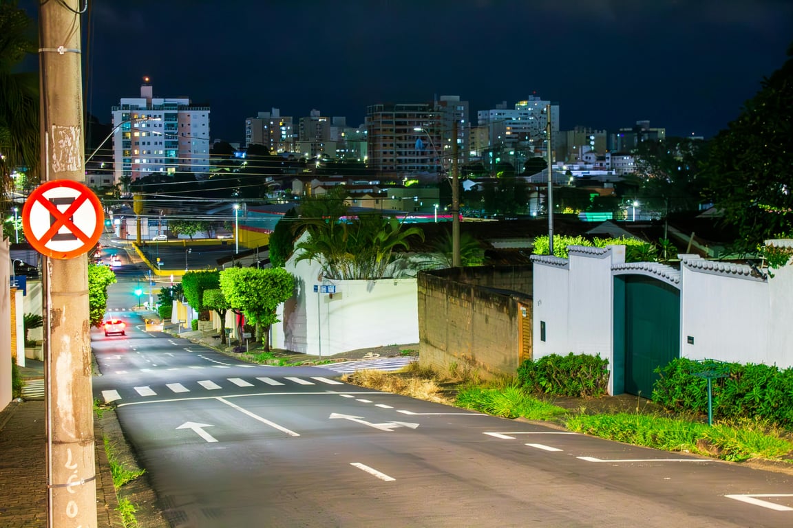 Vista urbana de Uberlândia à noite, com prédios e avenidas arborizadas iluminadas