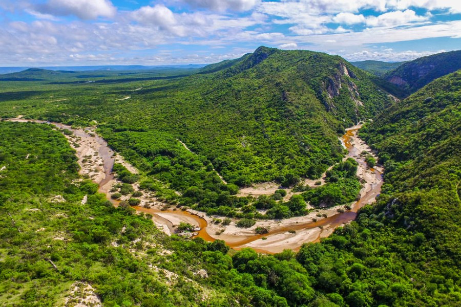 Paisagem do Seridó potiguar ao entardecer, com rio sinuoso e vegetação da caatinga