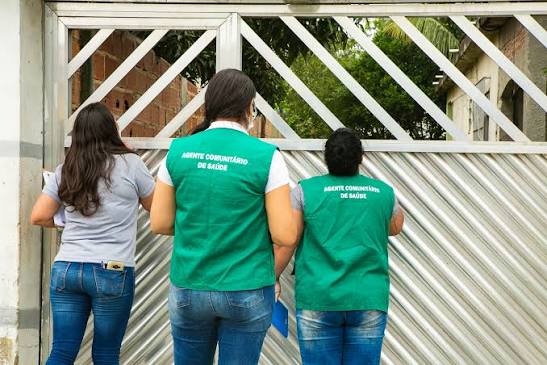 Profissionais de saúde comunitária em visita domiciliar em área urbana simples
