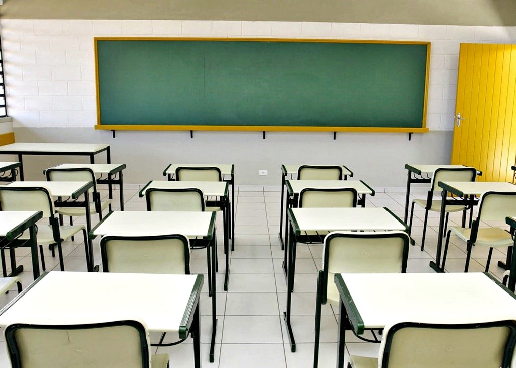 Sala de aula de escola pública com carteiras organizadas e lousa