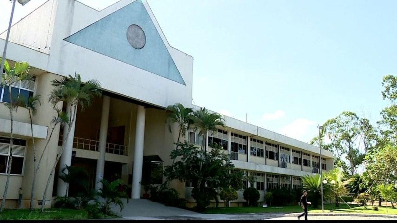 Fachada do Instituto Federal do Espírito Santo, com estudante caminhando em área externa do Campus Cariacica, em dia ensolarado