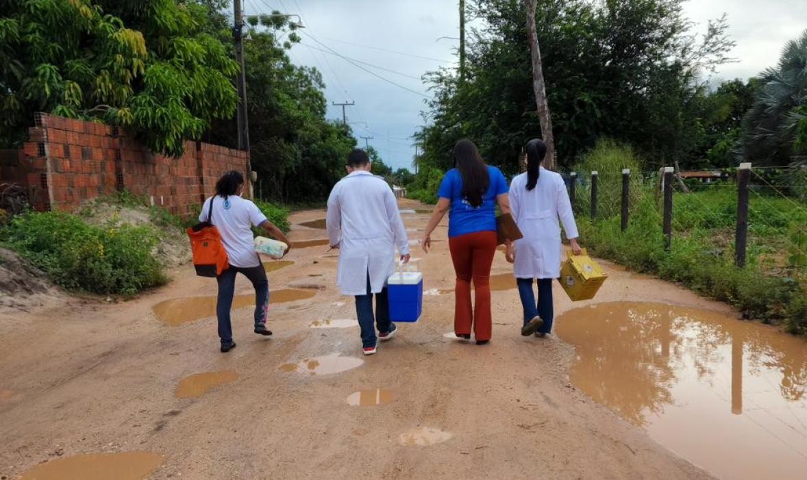 Agentes comunitários de saúde em atividade de campo, caminhando por via não pavimentada