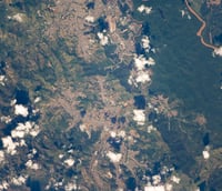 Vista aérea de Timóteo MG, com áreas verdes e parque industrial ao fundo.